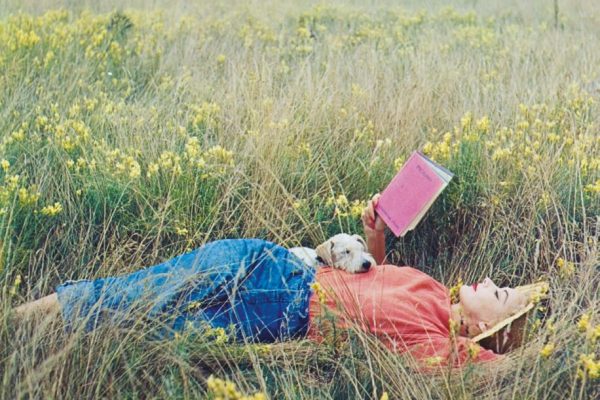Irving Penn, Lisa Fonssagrives-Penn lying in a field of grass, reading Gertrude Stein’s